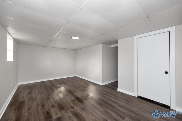 basement with dark wood-type flooring and a paneled ceiling