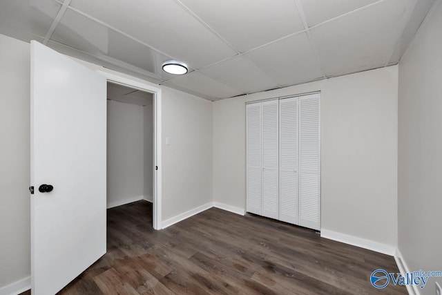 unfurnished bedroom featuring a paneled ceiling, dark hardwood / wood-style flooring, and a closet