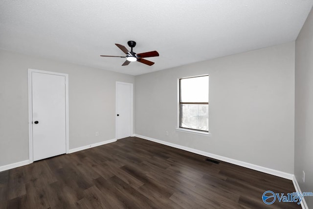 empty room featuring ceiling fan, dark hardwood / wood-style floors, and a textured ceiling