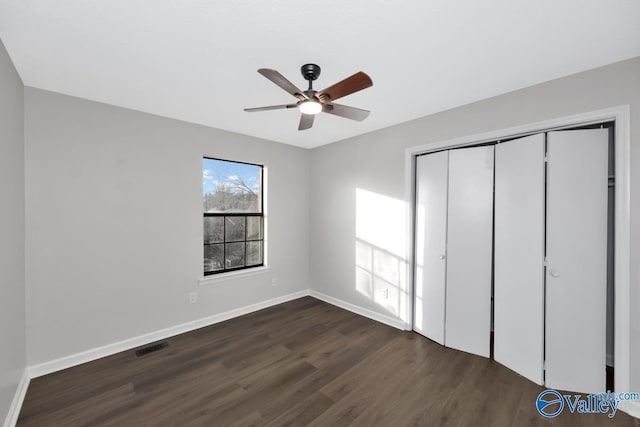 unfurnished bedroom with ceiling fan, dark hardwood / wood-style floors, and a closet