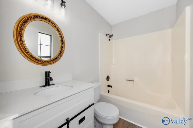 full bathroom with  shower combination, toilet, hardwood / wood-style floors, and vanity