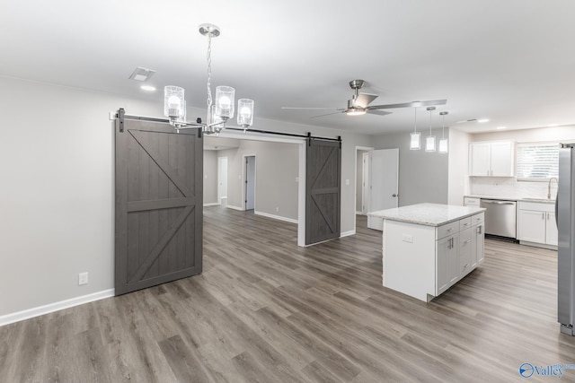 kitchen featuring a barn door, appliances with stainless steel finishes, white cabinets, and a center island