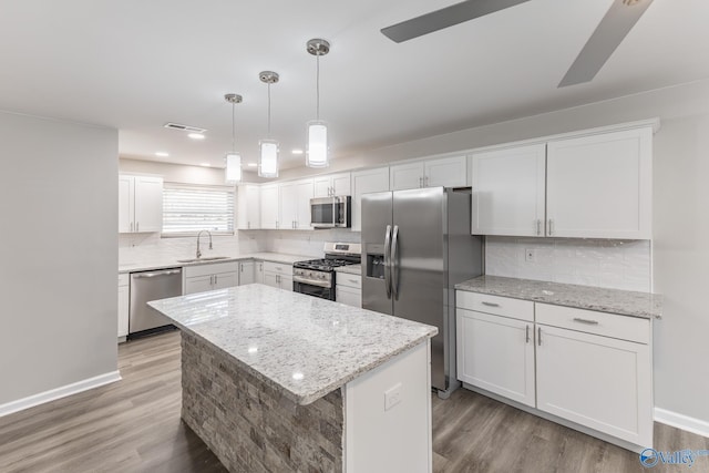 kitchen featuring light wood finished floors, appliances with stainless steel finishes, a sink, and tasteful backsplash