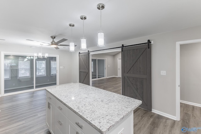 kitchen with a barn door, wood finished floors, a kitchen island, open floor plan, and pendant lighting