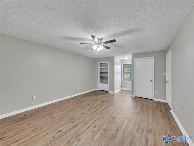 spare room with light wood-style floors, a textured ceiling, baseboards, and ceiling fan