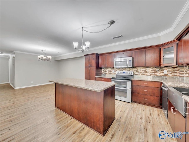 kitchen with a notable chandelier, stainless steel appliances, decorative backsplash, visible vents, and ornamental molding