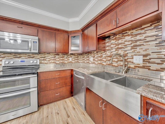 kitchen with crown molding, light wood-type flooring, a sink, backsplash, and stainless steel appliances