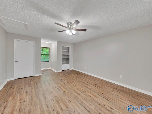 empty room with baseboards, a ceiling fan, a textured ceiling, and wood finished floors