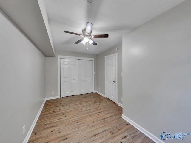 unfurnished bedroom with baseboards, ceiling fan, wood finished floors, and a closet