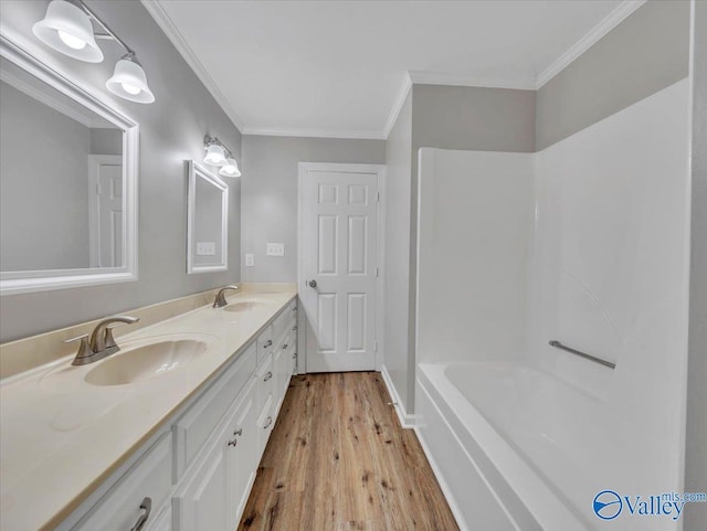 full bath with ornamental molding, a sink, and wood finished floors