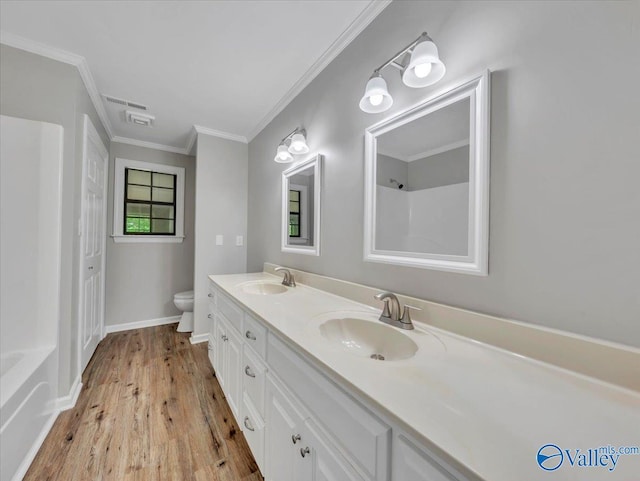full bathroom with a sink, wood finished floors, toilet, and ornamental molding