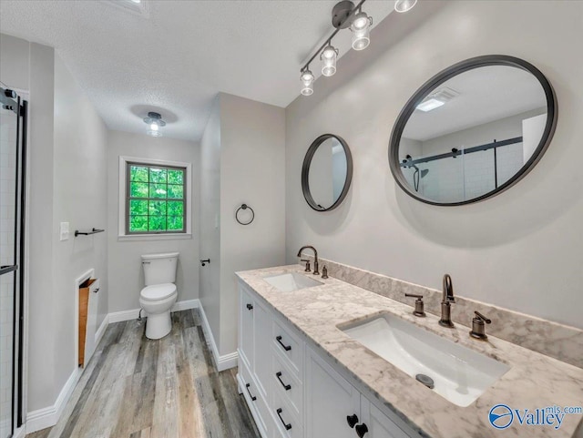 full bath featuring a sink, double vanity, toilet, and wood finished floors