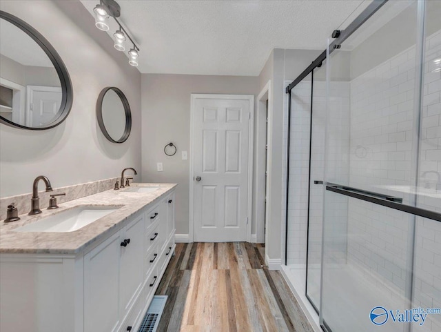 bathroom with wood finished floors, a sink, and a stall shower
