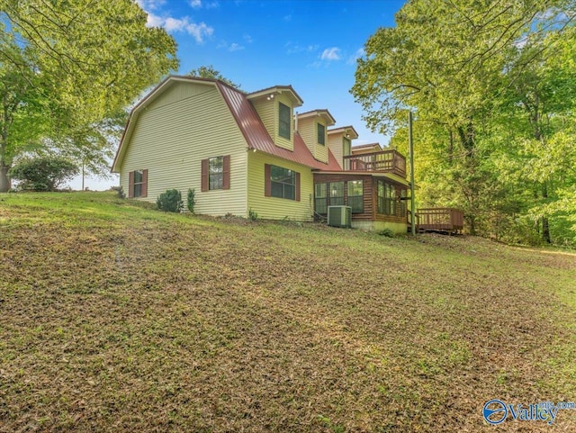rear view of property featuring a gambrel roof, a wooden deck, a sunroom, central air condition unit, and metal roof