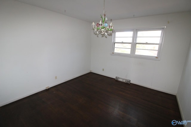 spare room featuring dark hardwood / wood-style floors and a chandelier