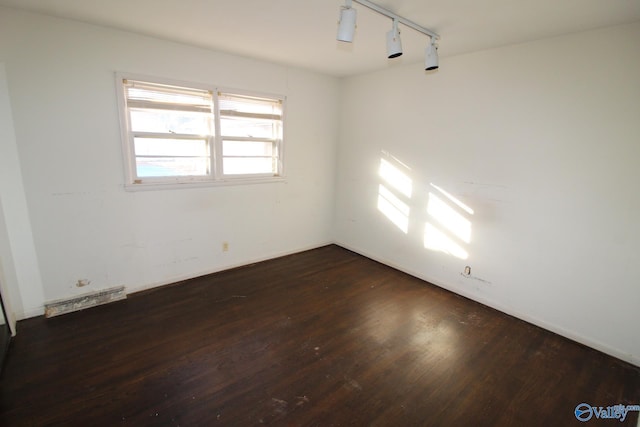 spare room featuring dark hardwood / wood-style flooring and rail lighting
