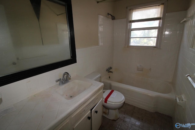 full bathroom with tiled shower / bath, vanity, toilet, and tile walls
