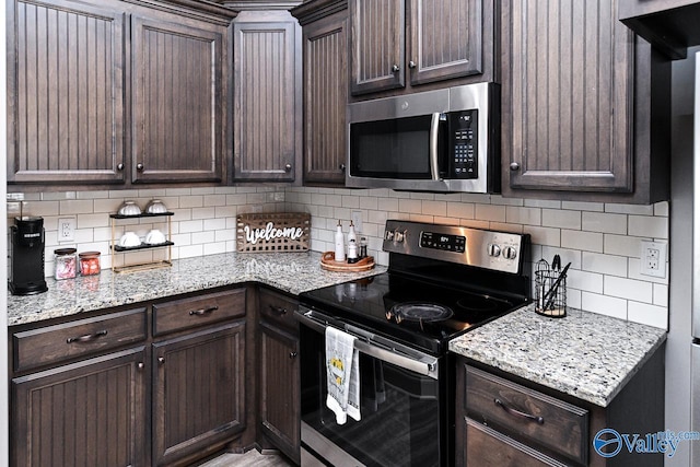 kitchen with dark brown cabinets, light stone countertops, appliances with stainless steel finishes, and tasteful backsplash