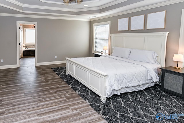 bedroom with ceiling fan, a raised ceiling, crown molding, and connected bathroom