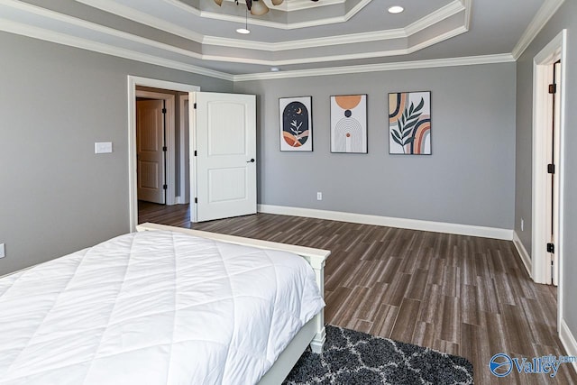 bedroom with dark wood-type flooring, a raised ceiling, and crown molding