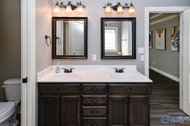 bathroom with wood-type flooring, vanity, toilet, and crown molding