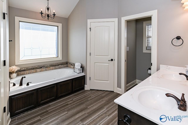 bathroom featuring vanity, lofted ceiling, a tub to relax in, wood-type flooring, and a chandelier