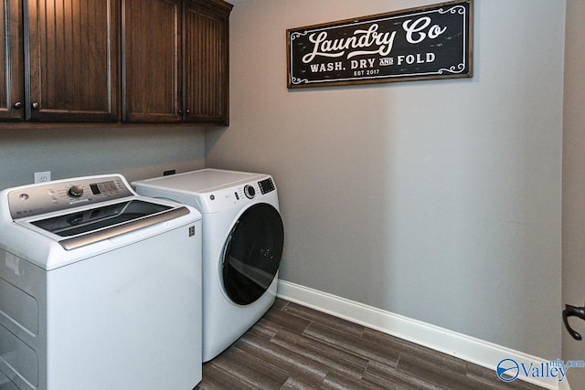 laundry area with cabinets, dark wood-type flooring, and washing machine and clothes dryer