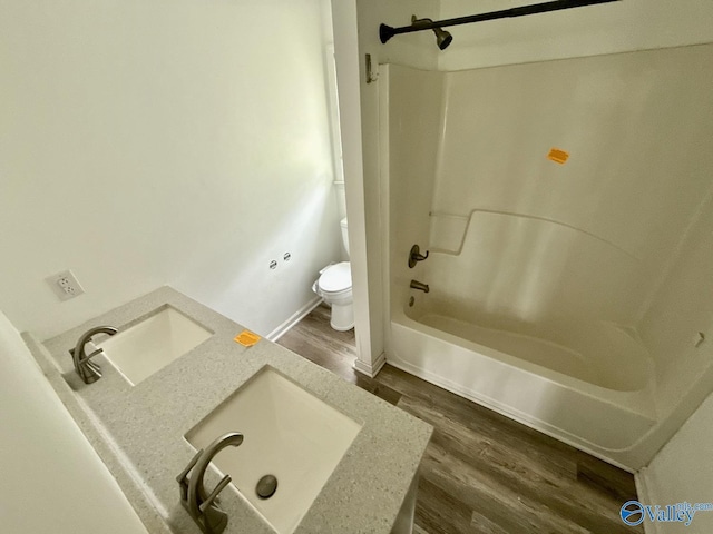 full bathroom featuring wood finished floors, a sink, toilet, and shower / washtub combination