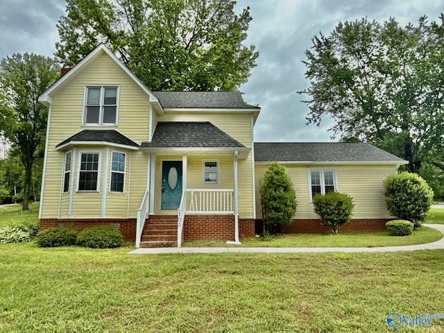traditional-style house featuring a porch, a front yard, and roof with shingles