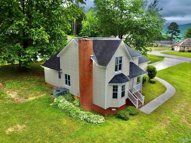 view of home's exterior with a shingled roof, a chimney, a yard, and cooling unit