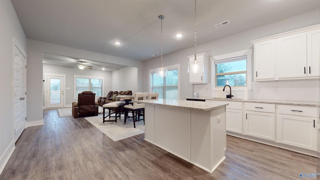 kitchen featuring sink, decorative light fixtures, white cabinets, and a kitchen island