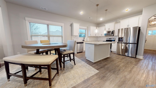 kitchen featuring white cabinetry, decorative light fixtures, a kitchen island, and appliances with stainless steel finishes