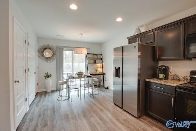 kitchen featuring light stone countertops, light wood finished floors, recessed lighting, black appliances, and dark brown cabinetry