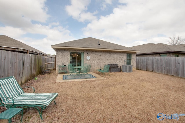 rear view of house featuring brick siding, a patio area, cooling unit, and a fenced backyard