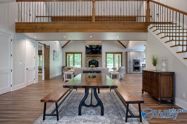 living room featuring a barn door, a fireplace, stairs, baseboards, and wood finished floors