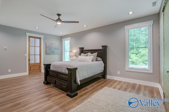 bedroom with a ceiling fan, baseboards, visible vents, and wood finished floors