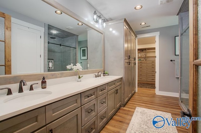 full bathroom with recessed lighting, a sink, wood finished floors, and a shower stall
