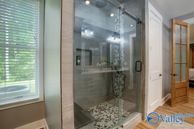 full bath with a shower stall, wood finished floors, and a wealth of natural light