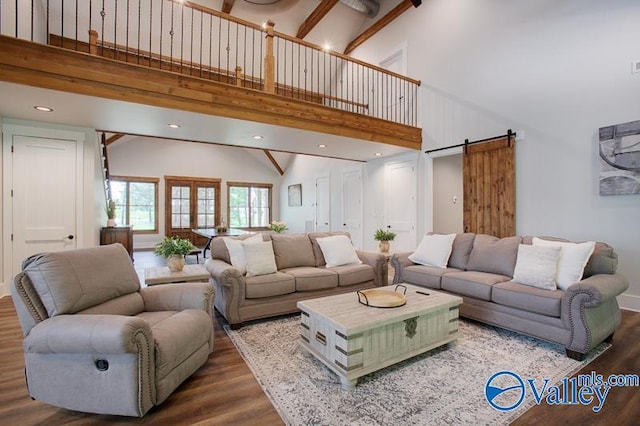 living room with a barn door, wood finished floors, and high vaulted ceiling
