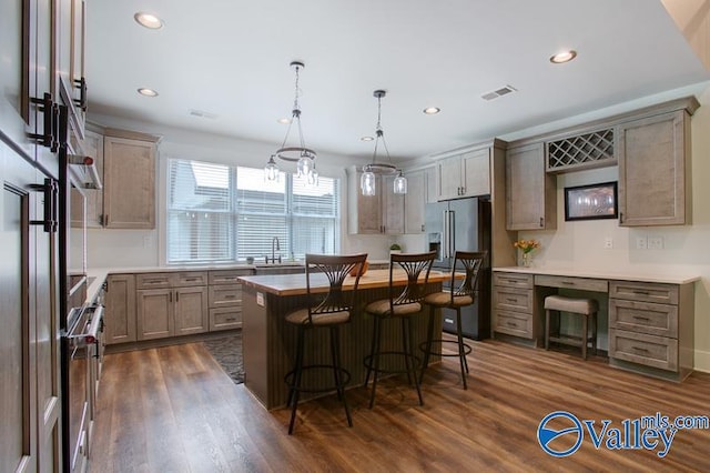kitchen featuring visible vents, dark wood finished floors, high end refrigerator, a breakfast bar, and recessed lighting