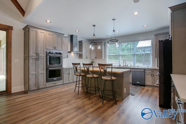 kitchen featuring wood finished floors, dishwasher, freestanding refrigerator, double oven, and wall chimney exhaust hood
