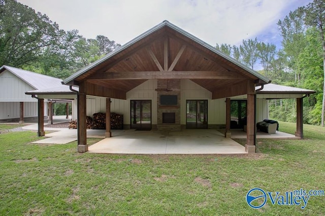 rear view of house featuring a lawn, a patio, a fireplace, and a carport