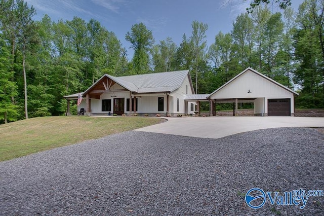view of front of house with concrete driveway, a front lawn, covered porch, metal roof, and an attached garage