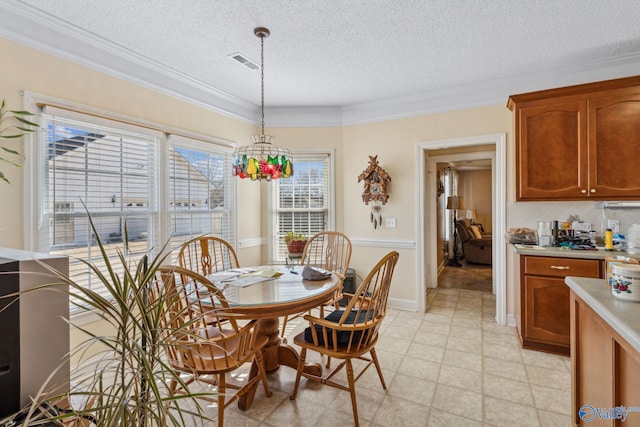 dining space with ornamental molding, a chandelier, and a textured ceiling