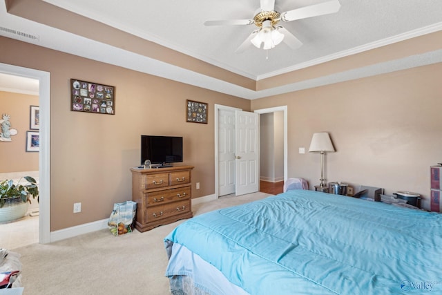 carpeted bedroom featuring a tray ceiling, crown molding, and ceiling fan