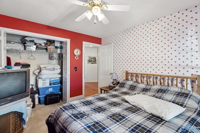 bedroom with ceiling fan, light carpet, a closet, and a textured ceiling