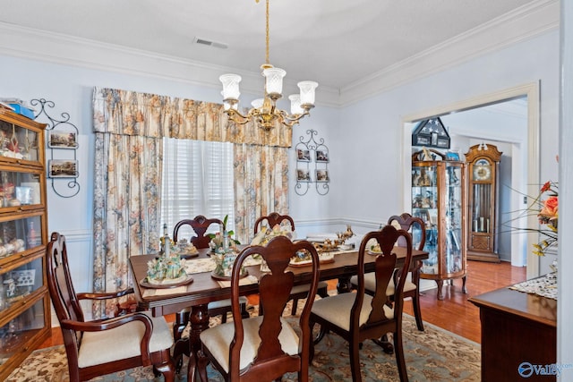 dining space with crown molding, hardwood / wood-style floors, and a chandelier