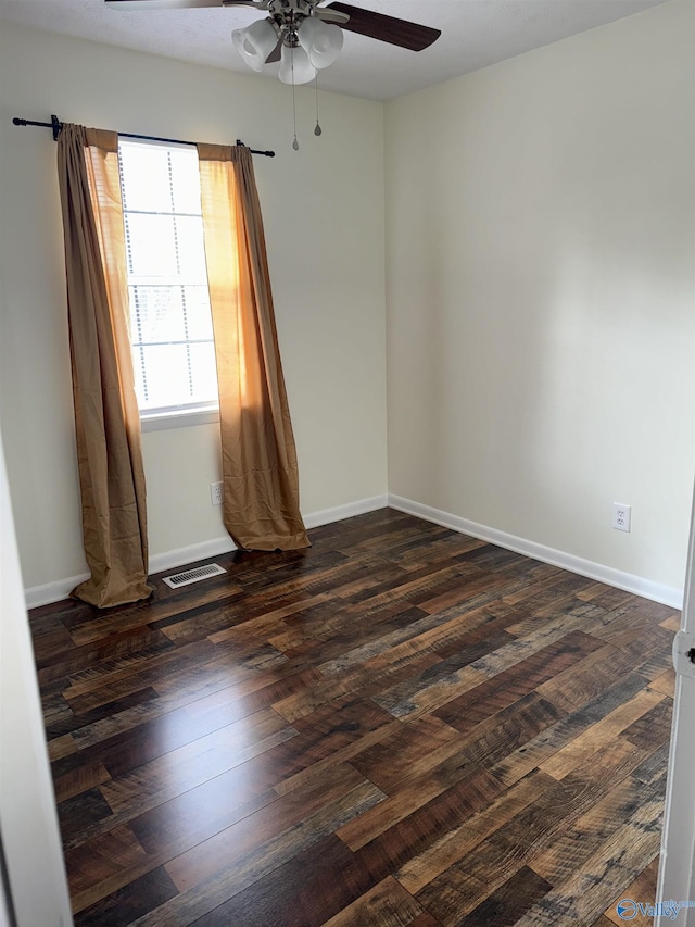 spare room with ceiling fan, dark wood finished floors, visible vents, and baseboards