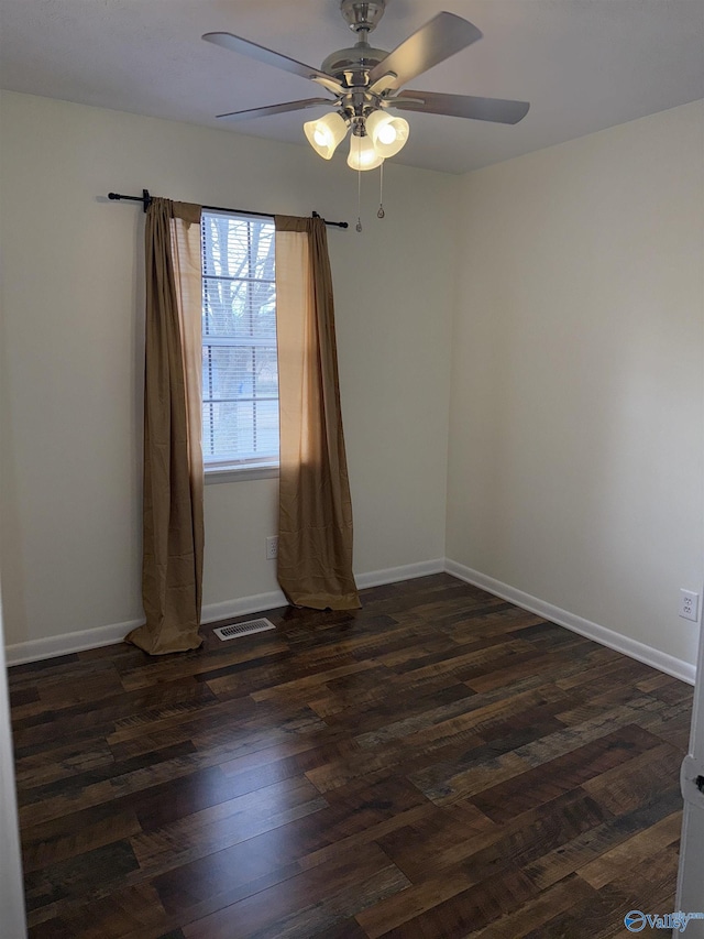 spare room featuring a ceiling fan, dark wood-style flooring, visible vents, and baseboards