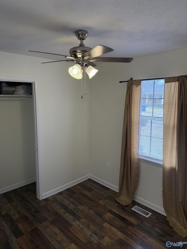 unfurnished bedroom with dark wood finished floors, visible vents, ceiling fan, a textured ceiling, and baseboards